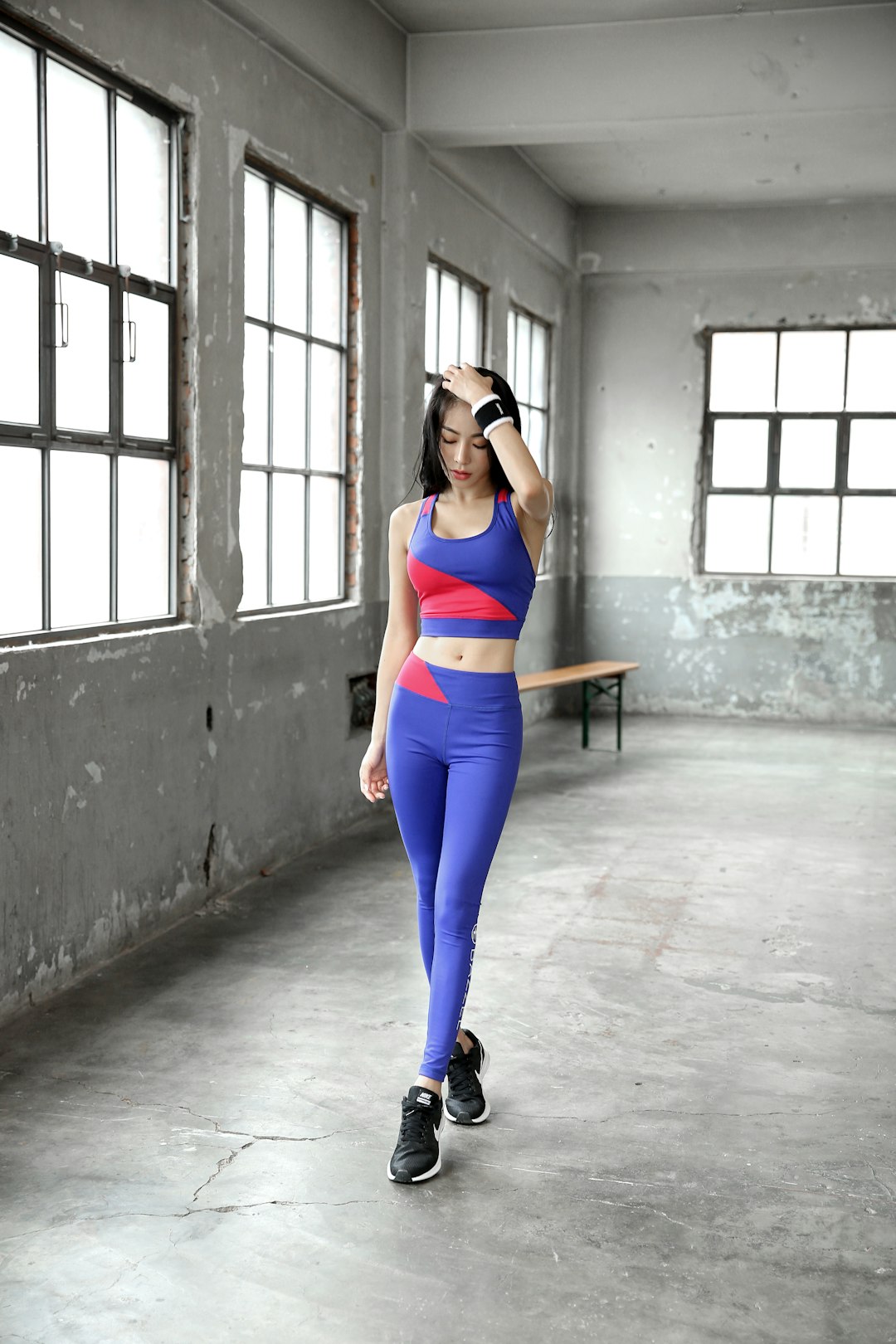 woman-in-blue-tank-top-and-blue-leggings-leaning-on-wall-ufyyc37yl-0